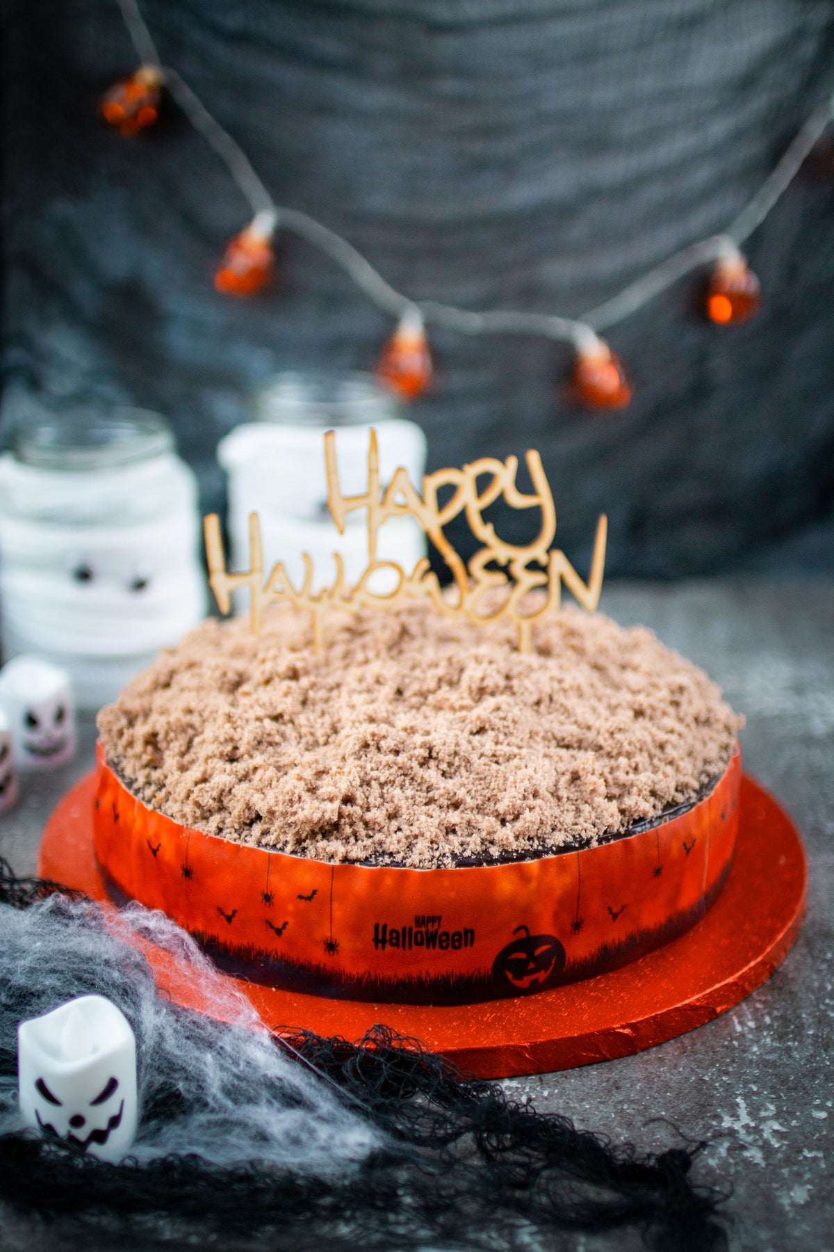 Halloween Tortenband auf Torte mit Kuchenstreuseln und CakeTopper Happy Halloween vor dunkler Wand