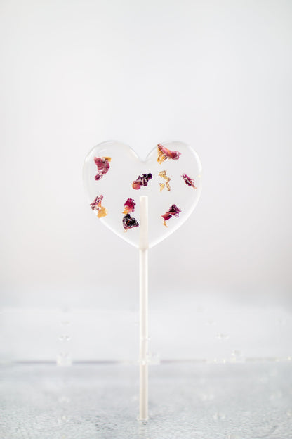 herzförmiger Blütenlolli mit roten Rosenblättern in Halter