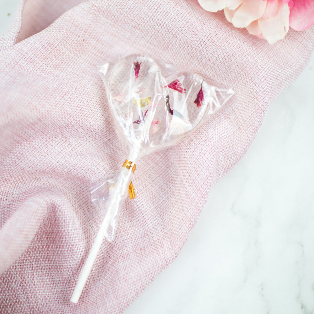 Blütenlolli in Herzform Exotic Crush auf rosa Tuch liegend