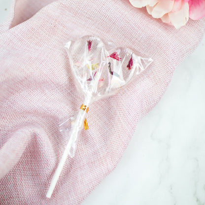 Blütenlolli in Herzform Exotic Crush auf rosa Tuch liegend