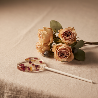 Blütenlolli Bloom Amour mit Rosenblütenblättern vor Rosenstrauß